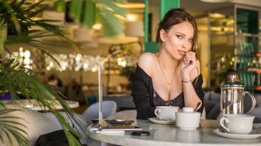 Genç kadın bir Cafe açık havada çay içme. Yaz şehir arka plan. Tonda fotoğraf.