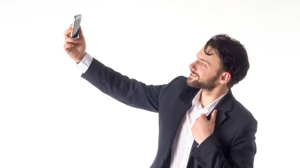 Guapo barbudo joven hombre de negocios tomando selfie sonriendo. retrato aislado sobre fondo blanco del estudio . — Foto de Stock