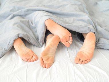 Bacaklar beyaz sayfalarda kucaklayan yatakta yalan aşk kapatın