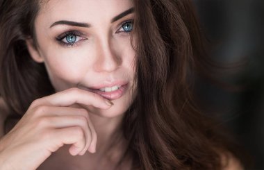 Finger ile Dudaklarına dokunmadan çekici bir genç kadın portresi yakın çekim.