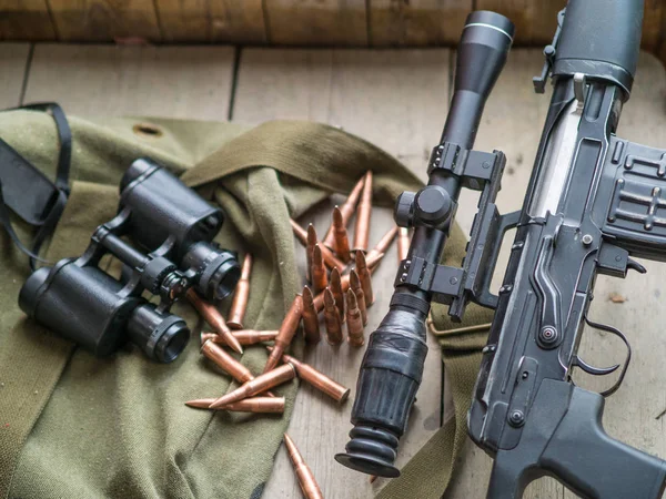 Odstřelovací puška, dalekohledy a munice na dřevěnou podlahu. — Stock fotografie