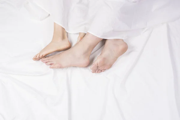 Close up of four feet in a bed — Stock Photo, Image