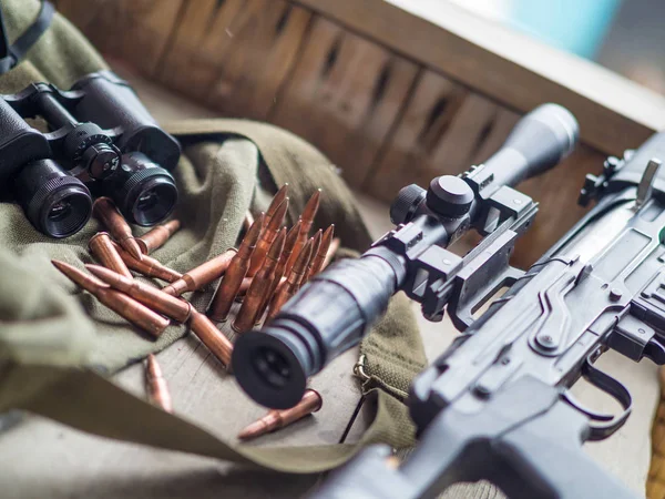 Espingarda de atirador, binóculos e munição que colocam em um piso de madeira — Fotografia de Stock