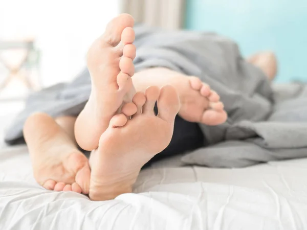 Close-up of the feet of a couple on the bed