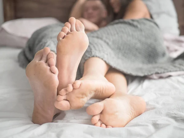 A man and a woman in bed. male and female legs side view, white linens — Stock Photo, Image