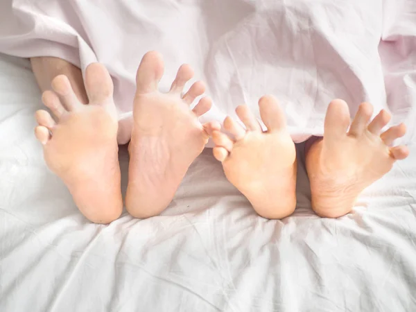 Close-up of the feet of a couple on the bed — Stock Photo, Image