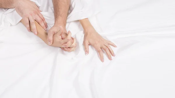 Four hands on the linens. Couple having sex on the bed — Stock Photo, Image