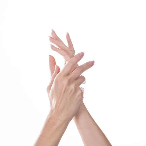 Mujer joven tocándose la mano y sintiendo efecto hidratante de la crema sobre fondo blanco — Foto de Stock