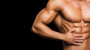 Fitness konsepti. Mükemmel karın kasları, pazıları ve göğsü olan kaslı ve formda bir genç. Siyah arka planda atletik vücudu olan iri yarı bir erkek..