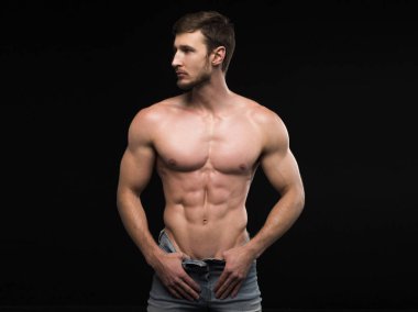 Çekici, üstsüz, şortlu, sarışın erkek vücut geliştirici. Kapalı bir spor salonunda, kaslı gövde ve yırtık karın kasları gösteriyor.