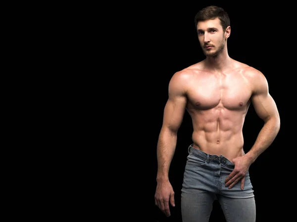 Çekici, üstsüz, şortlu, sarışın erkek vücut geliştirici. Kapalı bir spor salonunda, kaslı gövde ve yırtık karın kasları gösteriyor.