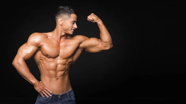 Jeune haltérophile sportif beau musculateur avec un corps idéal, après l'entraînement pose devant la caméra, muscles abdominaux, biceps triceps poitrine — Photo