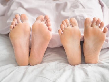 İnsan ayakları battaniyenin altında yatakta yatmaya closeup