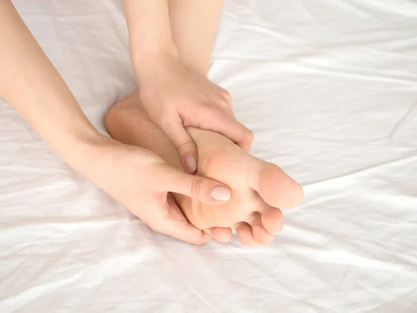 Pé Dor Perna de mulher sentada na cama em casa e paquerando seus pés. Conceito de cuidados de saúde e spa — Fotografia de Stock