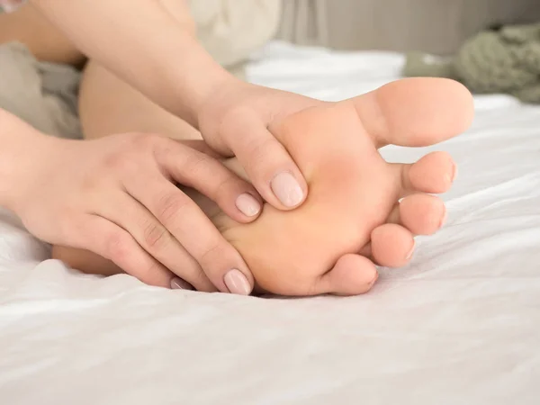 Pé Dor Perna de mulher sentada na cama em casa e paquerando seus pés. Conceito de cuidados de saúde e spa — Fotografia de Stock