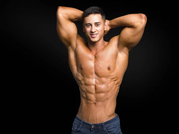 Handsome young muscular man shirtless wearing jeans, on dark background in studio shot — Stock Photo, Image
