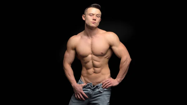 One handsome sexual strong young man with muscular body in blue jeans posing in studio on dark background — Stock Photo, Image