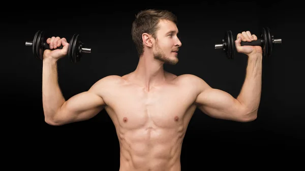 Junger Mann beim Porträttraining mit Stummglocke vor schwarzem Hintergrund — Stockfoto