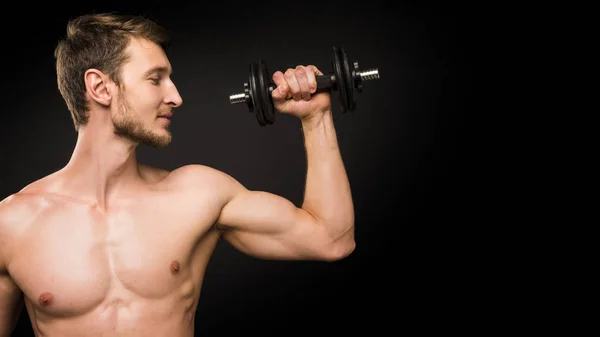 Selbstbewusster junger Mann beim Porträttraining mit Stummglocke vor schwarzem Hintergrund. — Stockfoto