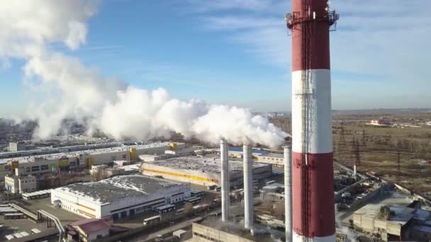 Strefa przemysłowa z dużą rurą czerwono-białą Gruby biały dym jest wylewany z rury fabrycznej w przeciwieństwie do słońca. Zanieczyszczenie środowisko: rura z dym. Widok z lotu ptaka — Wideo stockowe