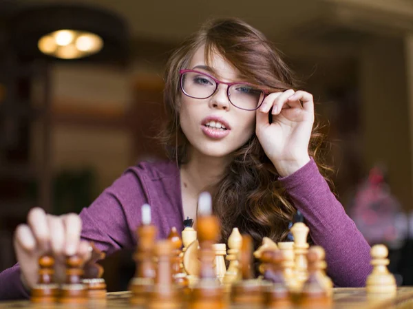 Close up de mulher de óculos jogando jogo de xadrez. Olha para a câmara. — Fotografia de Stock