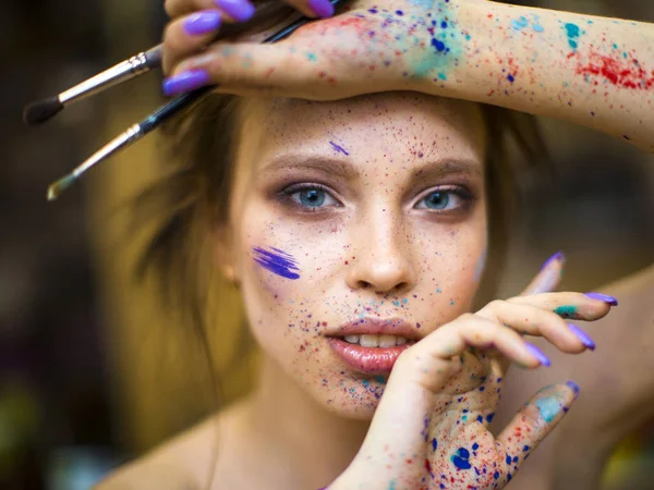 Portrait of artist woman with a drops of paints on her face — Stock Photo, Image