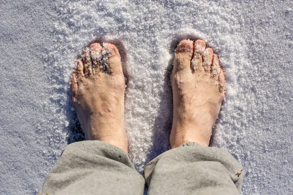 Male feet in the snow in sunny day, closeup