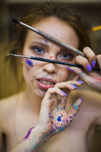 Portrait of artist woman with a drops of paints on her face — Stock Photo, Image