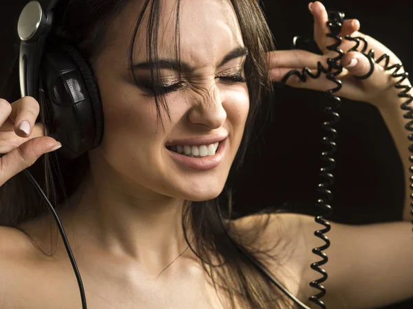 Close up retrato de uma mulher, que ouvindo a música em fones de ouvido com olhos fechados sobre fundo escuro — Fotografia de Stock