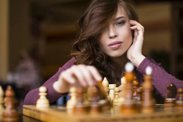 Beautiful brunette woman playing chess. Close up portrait, celective focus.