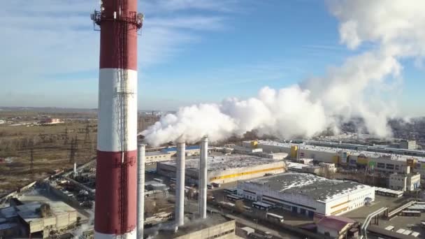 AERIAL: Zona industrial con una gran tubería roja y blanca se vierte humo blanco grueso de la tubería de fábrica en contraste con el sol. Contaminación del medio ambiente: una tubería con humo — Vídeos de Stock