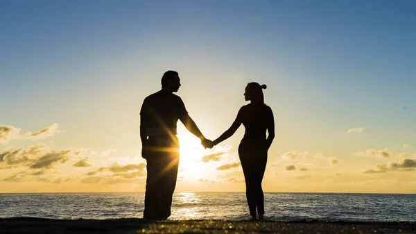 Ρομαντικό ζευγάρι στην παραλία στο πολύχρωμο ηλιοβασίλεμα στο παρασκήνιο — Φωτογραφία Αρχείου