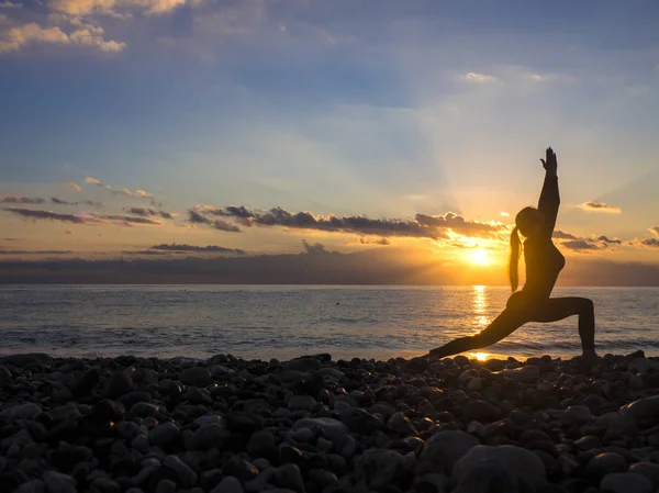 Mulher silhueta é jogar ioga excercise na praia com pôr do sol ou nascer do sol . — Fotografia de Stock