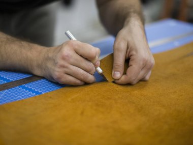 Eller, deri atölyesinde özel bıçak ile kesme kapatın. Adam konsantre uygunbir kumaş deri parçaları.