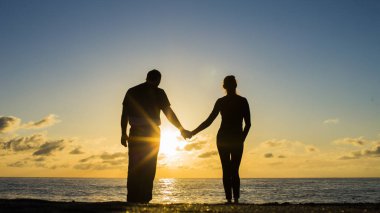 Arkadan sarılma ve güneş plaj izlerken birkaç siluet görünüşü