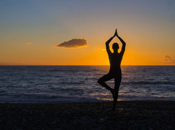 Mujer joven practicando yoga en la playa al atardecer — Foto de Stock