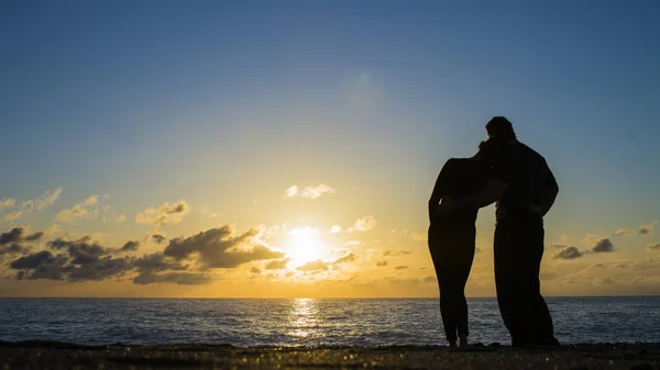 Οπίσθια όψη των ζευγών σιλουέτα αγκάλιασμα και βλέποντας ήλιο στην παραλία — Φωτογραφία Αρχείου