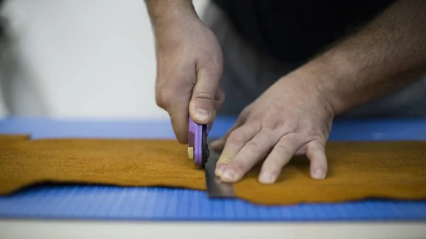 Man aan het werk met leer met behulp van crafting tools. Close-up van mannetjes handen snijden van leder — Stockfoto