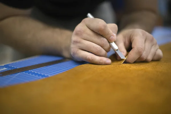 Mãos masculinas cortando couro em uma oficina, de perto — Fotografia de Stock