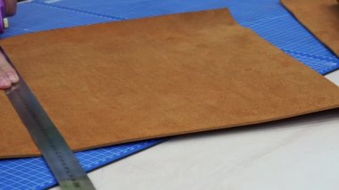 Deri usta bir el yapımı hakiki deri çanta yapmak. Ellerini dönen bir bıçak ve bir parantez ile deri kameraya doğru kesme yakın çekim