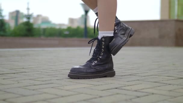 Primer plano de piernas femeninas caminando con botas de armi pesadas. Primer plano tiro femenino de moda en botas de cuero caminar en la calle en piedra . — Vídeos de Stock