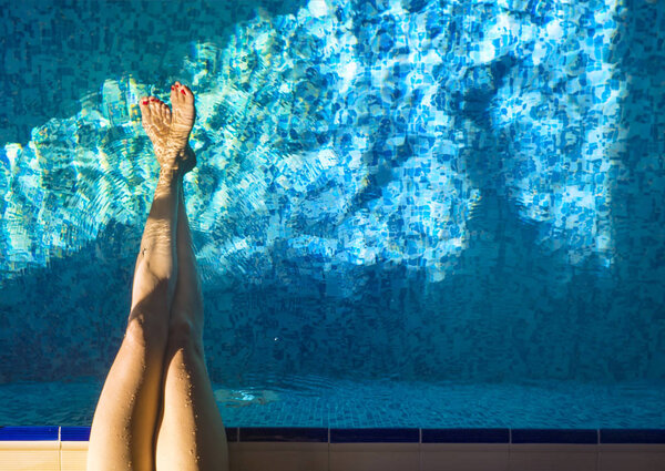 Female legs in the pool water. Activity and healthy life concept. Active rest and holidays.