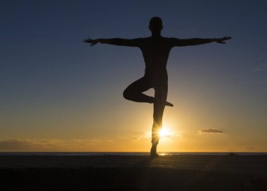 Meditasyon yoga poz güzel gün batımını bakan bir genç kadın. Zihin beden ruh kavramı.