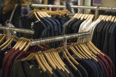 Bir tasarımcı giyim mağaza rafındaki giyim asmak. Alışveriş ve satış konsepti.