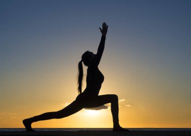 Siluet genç kadın günbatımı veya gündoğumu yüzme havuzu ve doğa deniz üzerinde poz yoga uygulamak. Yoga ve sağlıklı kavramı