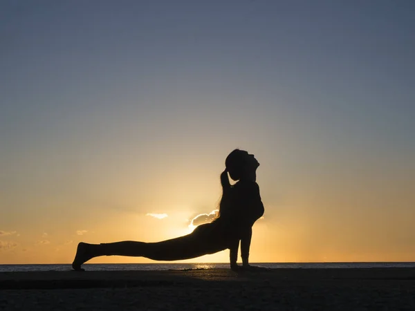 Silhueta jovem praticando pose ioga na piscina e na praia da natureza ao pôr-do-sol ou nascer do sol. Yoga e conceito saudável — Fotografia de Stock