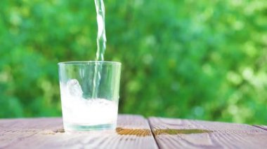 Gazlı mineral su bulanık cam ağaç yaprakları arka planda, sağlıklı yaşam kavramı içine dökülen