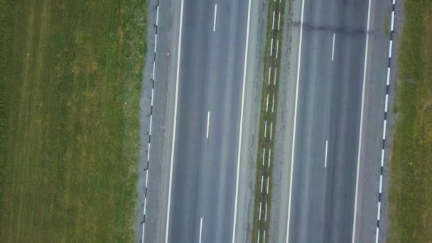 Vista aérea de várias estradas paralelas no meio da zona do parque no verão. Drone cinematográfico disparado voando sobre a estrada com tráfego em campos verdes . — Vídeo de Stock