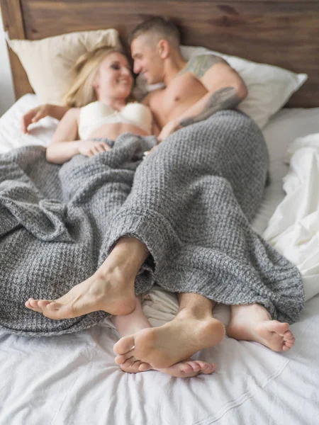 As pernas de um jovem casal heterossexual relaxando na cama. Foco seletivo, foco nas pernas . — Fotografia de Stock
