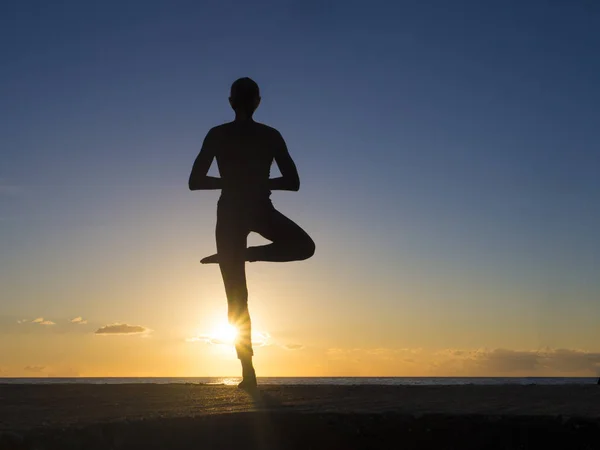 Jovem mulher saudável praticando ioga exercício de fitness na praia ao pôr do sol. Conceito de estilo de vida saudável. Texto espaço cópia . — Fotografia de Stock